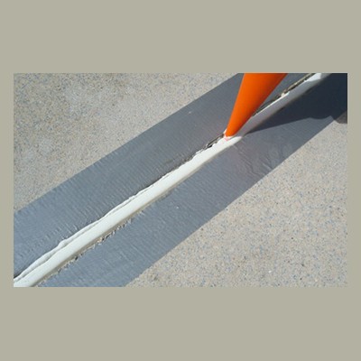 Expansion Joint Caulking Orange cone marking a crack on a concrete surface filled with white sealant.
