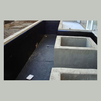 Planter Waterproofing Concrete planters on a black waterproofed structure, with unfinished walls and construction materials visible nearby.