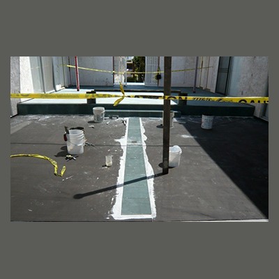 Under Tile Waterproofing Construction site with caution tape, buckets, and tools on a partially painted surface.