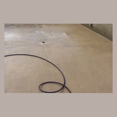 Water Testing A coiled black cable lays on a plain concrete floor with a small circular hole near the center.